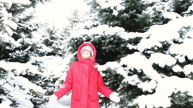 Cheerful young woman shoots snow from trees, jumps and shakes snow from a branch