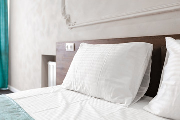 Bed maid-up with clean white pillows and bed sheets in beauty room.