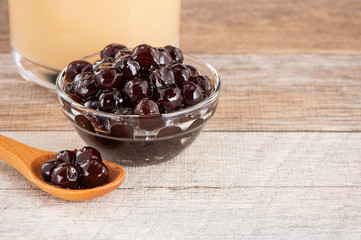Tapioca Pearl , Bubble topping for tea or other beverage, in a cup, place on wooden table. Copy space