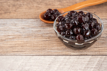 Tapioca Pearl , Bubble topping for tea or other beverage, in a cup, place on wooden table. Copy space