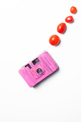 pink camera with tomatoes, hipster concept on white background