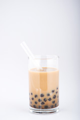 A glass of sweet milk bubble tea with tapioca pearls, and straw on white background. Copy space
