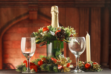 Champagne bottle with wine glasses and candles on fireplace background
