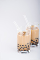 A glass of sweet milk bubble tea with tapioca pearls, and straw on white background. Copy space