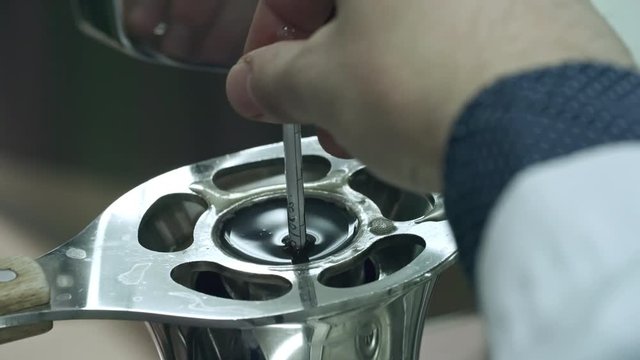 Close-up of hand of brewery worker putting hydrometer into steel cylinder for measuring beer gravity