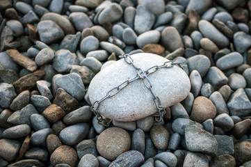 Fototapeta na wymiar A huge stone tied with a metal chain
