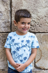 Little boy in front of a wall outdoors