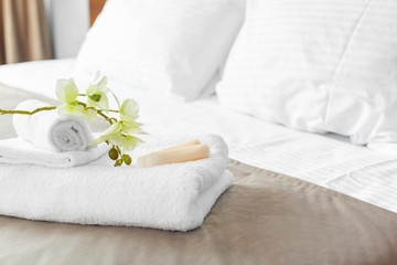 towels and flower on bed in hotel room - obrazy, fototapety, plakaty