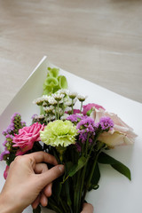 pink bouquet of carnations and roses. woman florist making bouquet of flowers indoor. Female florist preparing bouquet  in flower shop. Close up. Mother's Day and Valentine's Day concept 