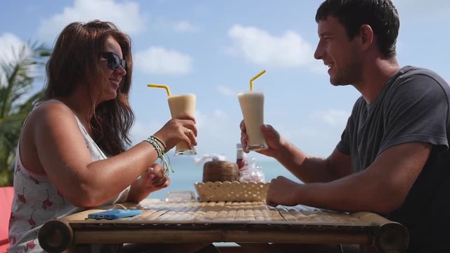 A date in an outdoor cafe, the couple are minted by glasses with delicious drinks. Slow motion, HD, 1920x1080