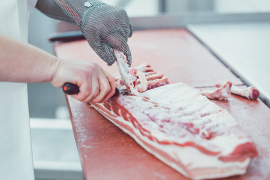 Butcher Cutting Meat For Further Processing With Knife In Butchery