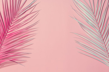 Painted palm leaves on pastel pink background with copy space. Tropical summer concept. Minimal flat lay.