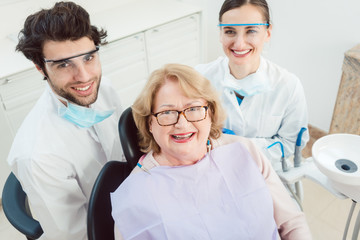 Obraz premium Dentists and patient in surgery looking at camera smiling 