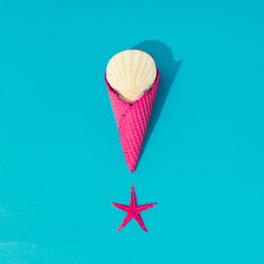 Creative summer layout with sea shells and icecream cone on bright blue background. Minimal beach food concept. Flat lay.