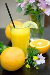 Glasses with fresh orange juice and fruit on table.