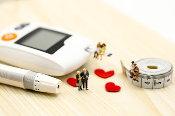 Miniature people : doctor and couple oldman with glucose meter with lancet and mini heart, j,medicine, diabetes, health care concept.
