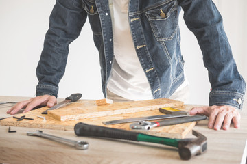 Carpenter working carefully looking at the plans work in carpentry. He is successful entrepreneur at his workplace. hammering a nail Supports On Building Site work with cutter.