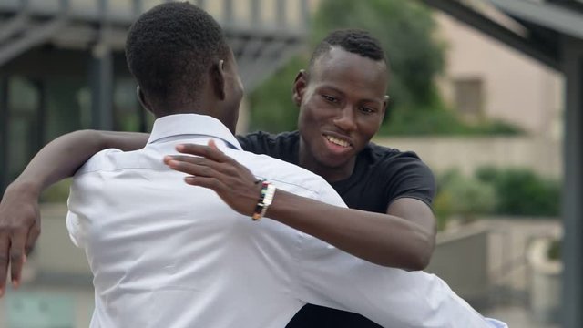 African black men greeting and hugging in the street- slow motion