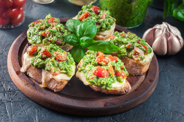 Bruschetta with fresh pesto, mozzarella and cherry tomatoes on cutting board
