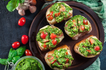 Bruschetta with fresh pesto, mozzarella and cherry tomatoes on cutting board