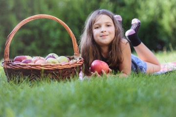 Obraz na płótnie Canvas Cute little girl lying in grass with apple basket