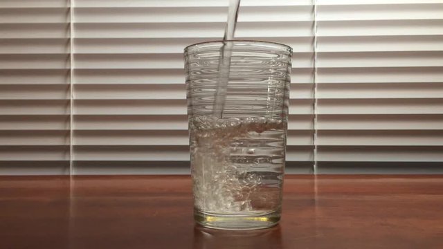 Pouring water into a glass and popping in two asprin