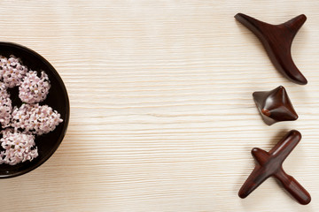 Special wooden massage sticks lying in row, bowl with flowers on wooden background with copy space.