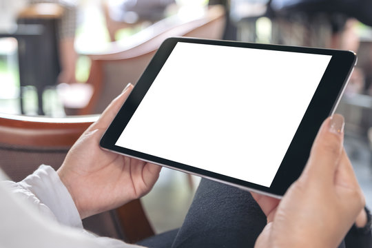 Mockup image of hands holding black tablet pc with white blank desktop screen in cafe