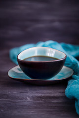 Black coffee in a turquoise cup on a black background. Low key, free space