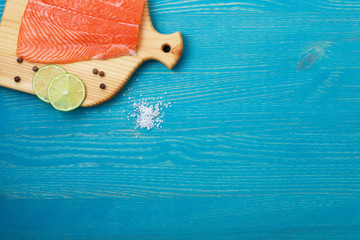 Cutting board with salmon on wooden background top view.