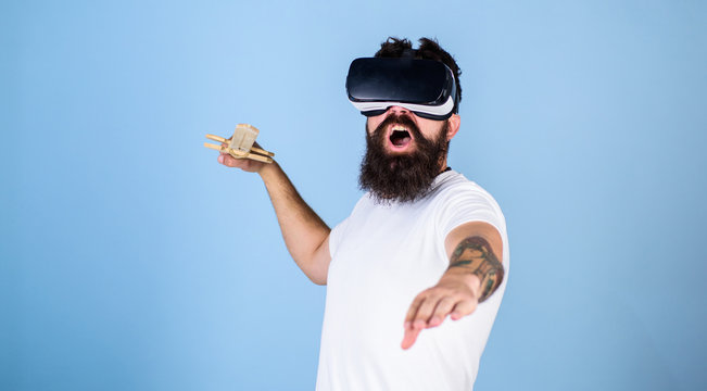Hipster on shouting face enjoy play game in virtual reality. Man with beard in VR glasses, light blue background. VR gamer concept. Guy with head mounted display and sword play fighting game in VR