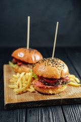 homemade juicy burgers on wooden board. Street food, fast food.  with French fries