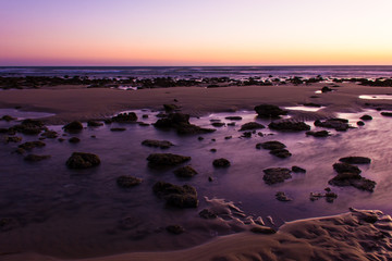 Rocky shore on shallow water at low tide at magnificent sunset in Zahora beach, Cadiz. Splendid twilight by the sea in Andalusia, Spain