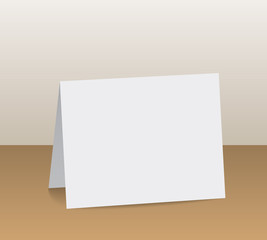 Realistic white blank folded paper card standing on wooden table top
