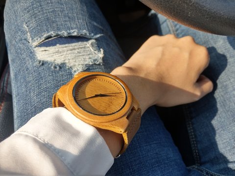 hand of caucasian women wearing wood watch with jean pants background