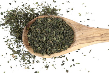 Dry, cut and sliced nettle pile in wooden spoon, isolated on white background, top view