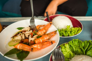 delicious thailand food fried shrimp and squid cooked herb in dish with rice on wooden table background