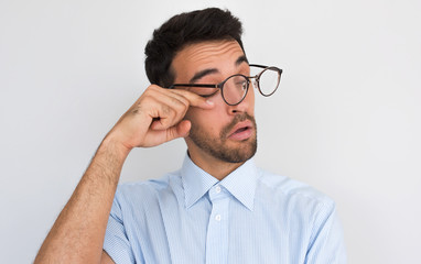 Closeup image of handsome bored sleepy unshaven male after long overwork in office, wants to sleep, wearing round spectacles and blue shirt isolated on white studio background with copy space.