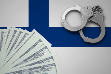 Finland flag  with handcuffs and a bundle of dollars. The concept of illegal banking operations in...