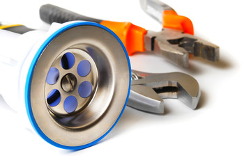 closeup of kitchen drain assembly and plumbing tools on white background