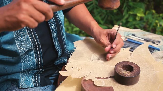 Close up of leather puppet Wayung kulit maker man working outdoors in Jogjakarta, Indonesia