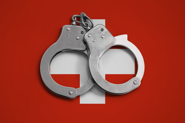 Switzerland flag  and police handcuffs. The concept of observance of the law in the country and...