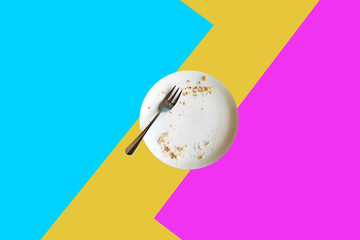 Empty plate with crumbs after eating on a bright colored background. The concept of the end of the holiday or celebration