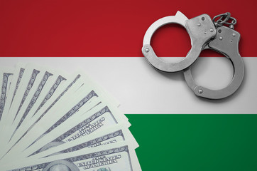Hungary flag  with handcuffs and a bundle of dollars. The concept of illegal banking operations in...