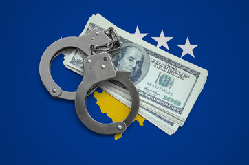 Kosovo flag  with handcuffs and a bundle of dollars. Currency corruption in the country. Financial crimes