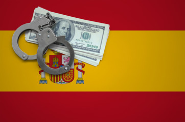Spain flag  with handcuffs and a bundle of dollars. The concept of breaking the law and thieves...
