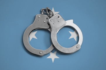 Micronesia flag  and police handcuffs. The concept of observance of the law in the country and...