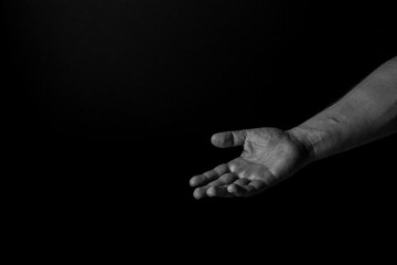 Hand of a man palm up reaching, isolated on black background, giving a helping hand. Give me your hand concept.