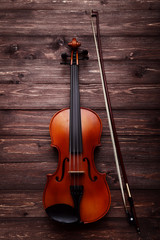 Fototapeta na wymiar Violin with bow on brown wooden table