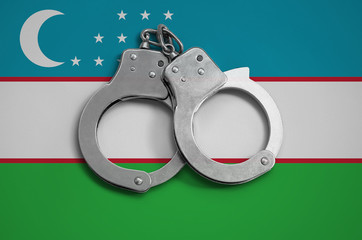 Uzbekistan flag  and police handcuffs. The concept of observance of the law in the country and...